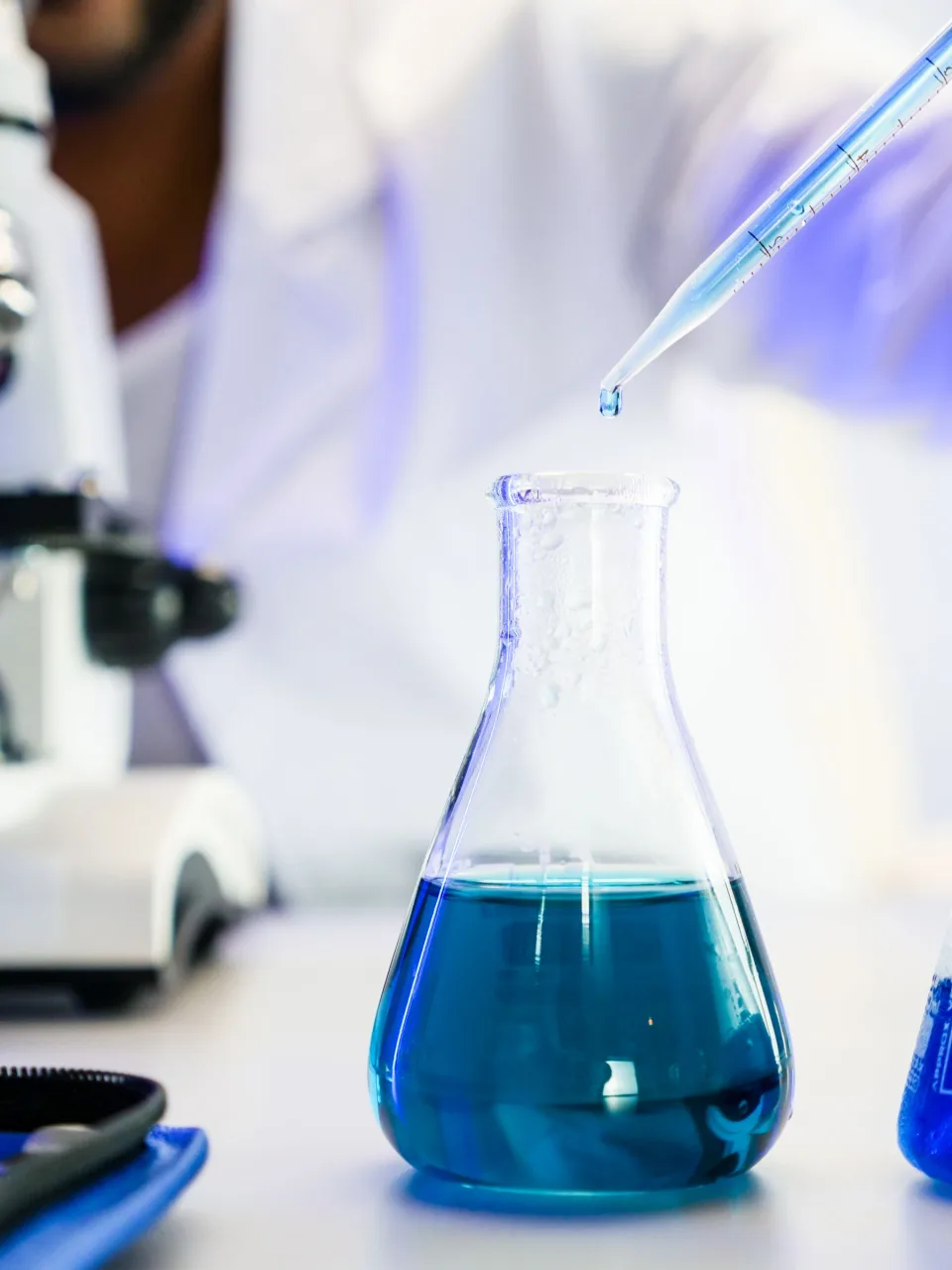 Pipeta depositando una muestra en un matraz de laboratorio