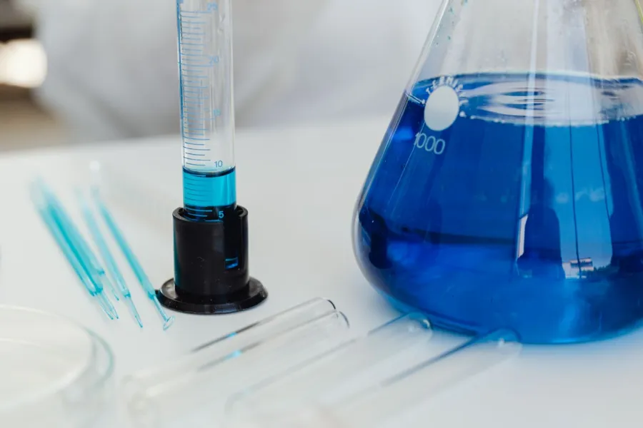 Cristalería graduada con solución azul en una mesa de laboratorio