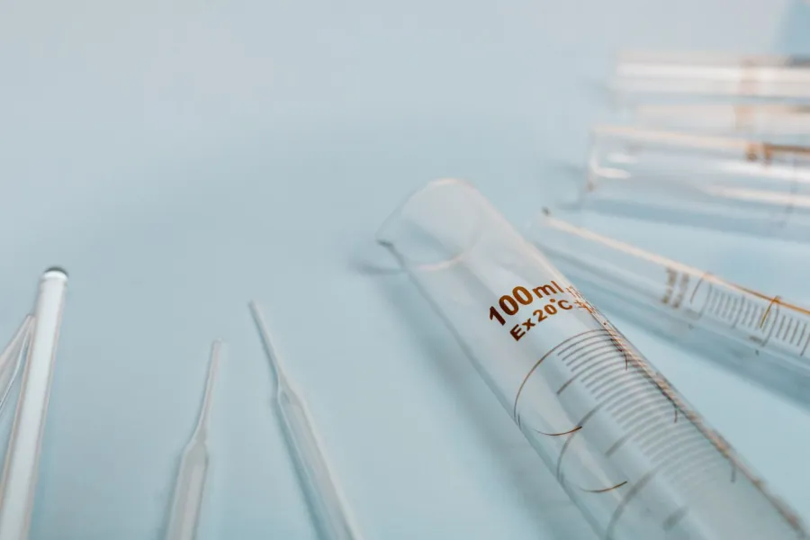 Tubos y pipetas de vidrio sobre una superficie celeste